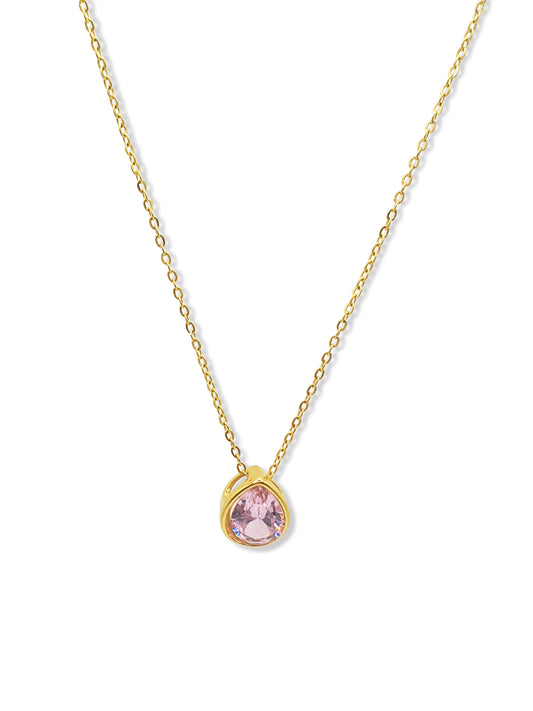 A gold necklace with a teardrop pendant set with a pale pink stone hangs against a white background