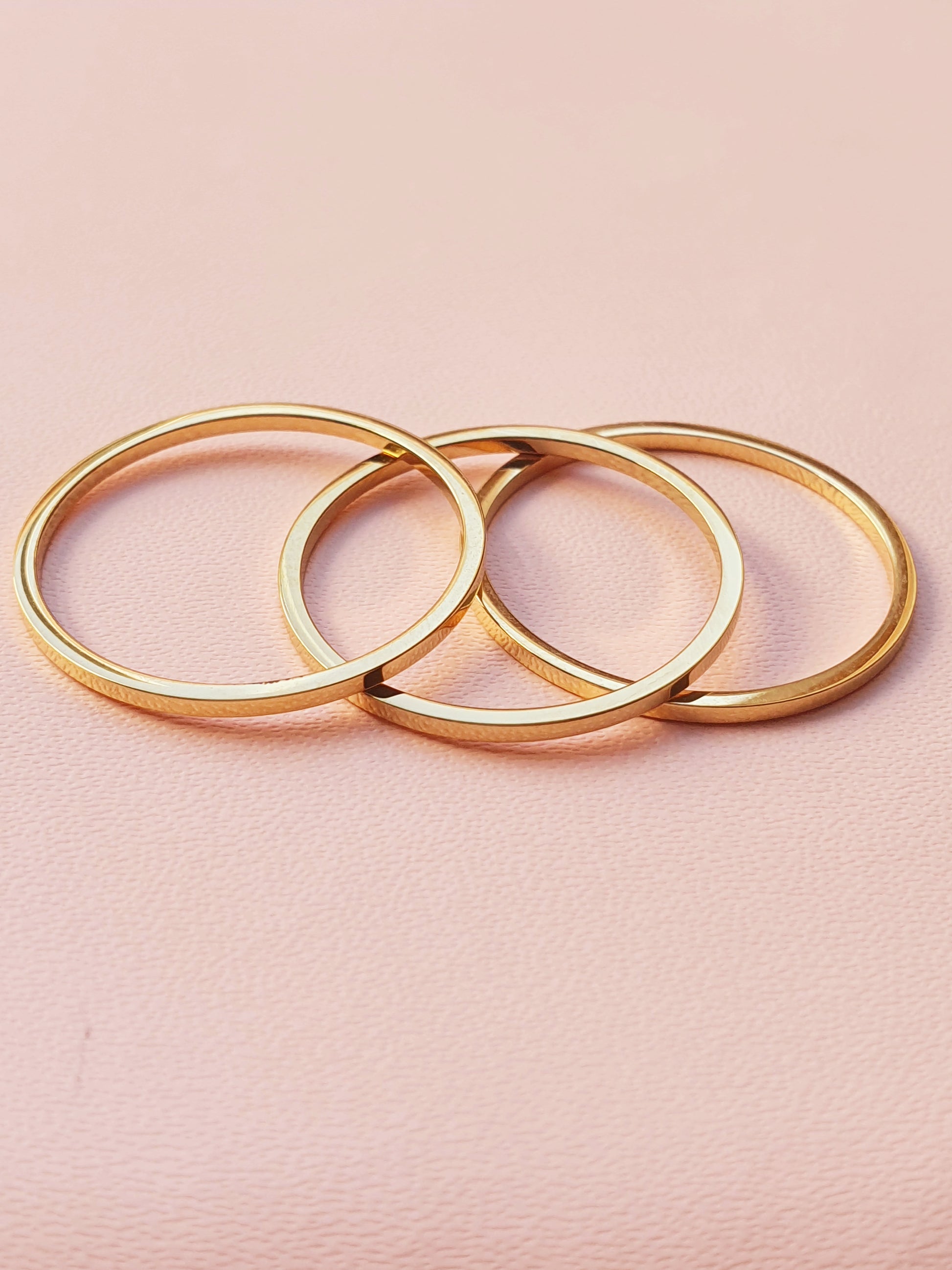 Three slim gold stacking rings placed on top of each other