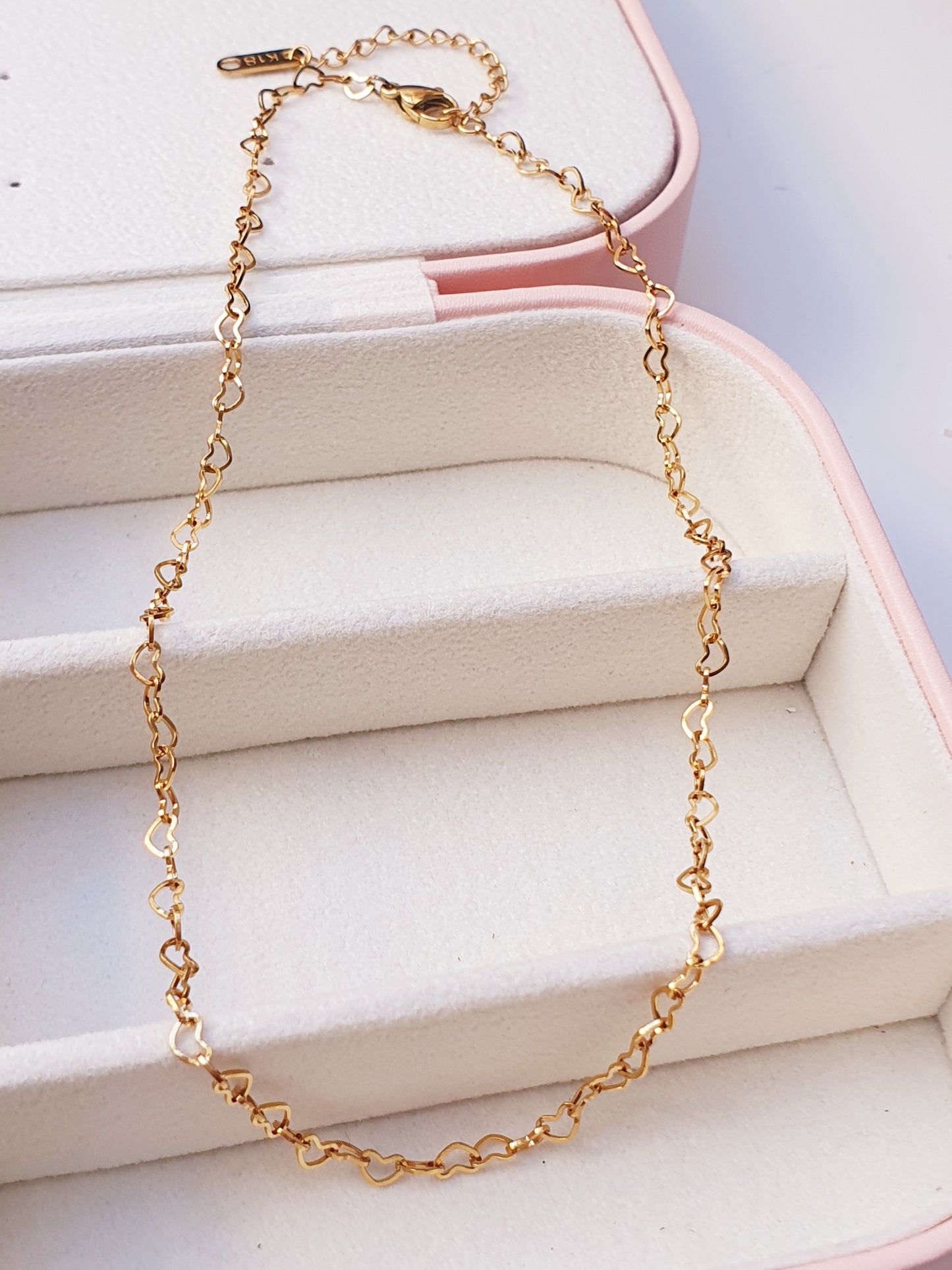 Gold choker made up of heart shaped chain links resting on a jewellery box